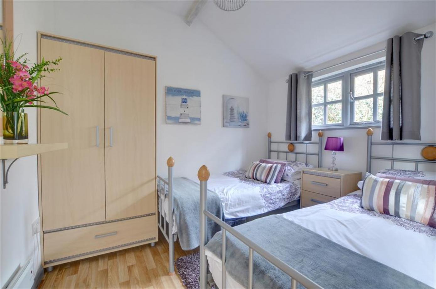 A bedroom with two single beds and a wardrobe in one of the Cranbrook Holiday lets for accomodation in Kent.