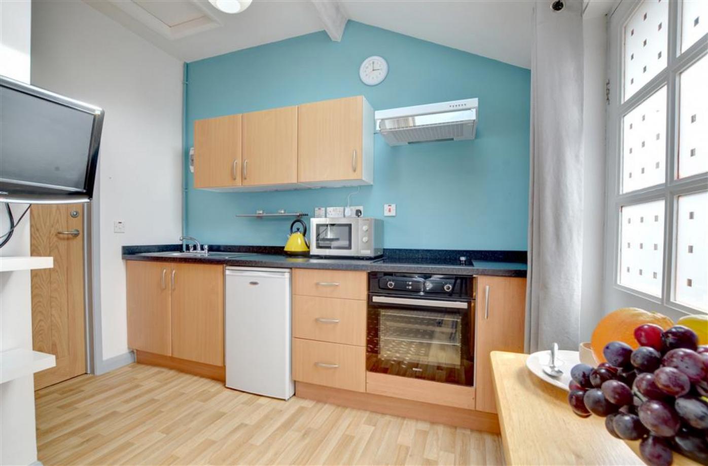 The fully equipped kitchen in one of the Cranbrook holiday lets, showing an oven, a microwave, a fridge a sink and cupboards for accomodation in Kent..