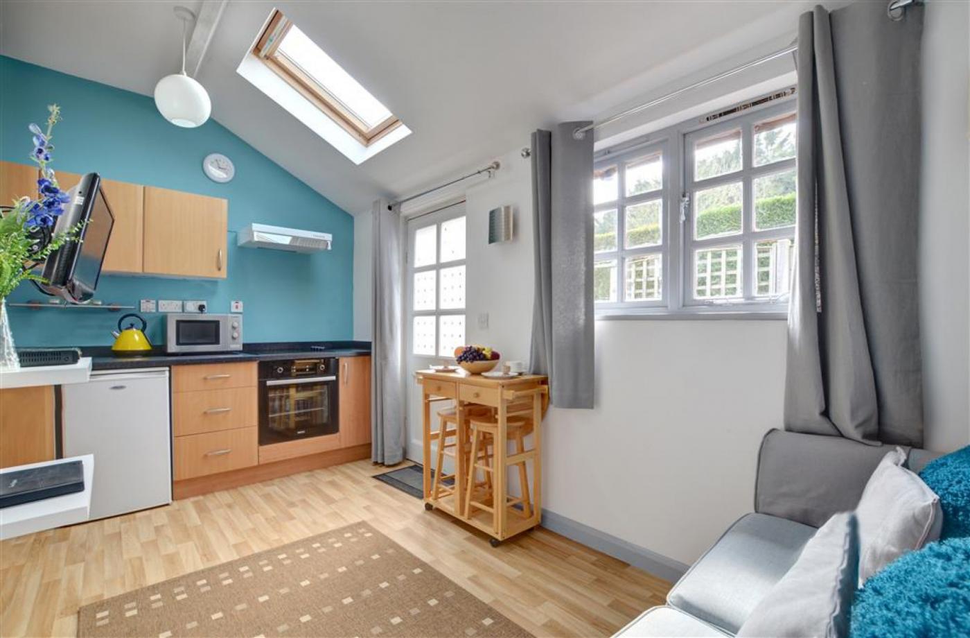 The sitting room in the apartments in between Cranbrook and Staplehurst, shows a sofa, the kitchen and a high table and stalls for accomodation in Kent..