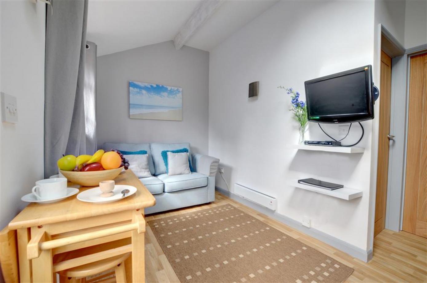 The sitting room in the apartments in between Cranbrook and Staplehurst, shows a sofa, the kitchen and a high table and stalls for accomodation in Kent..